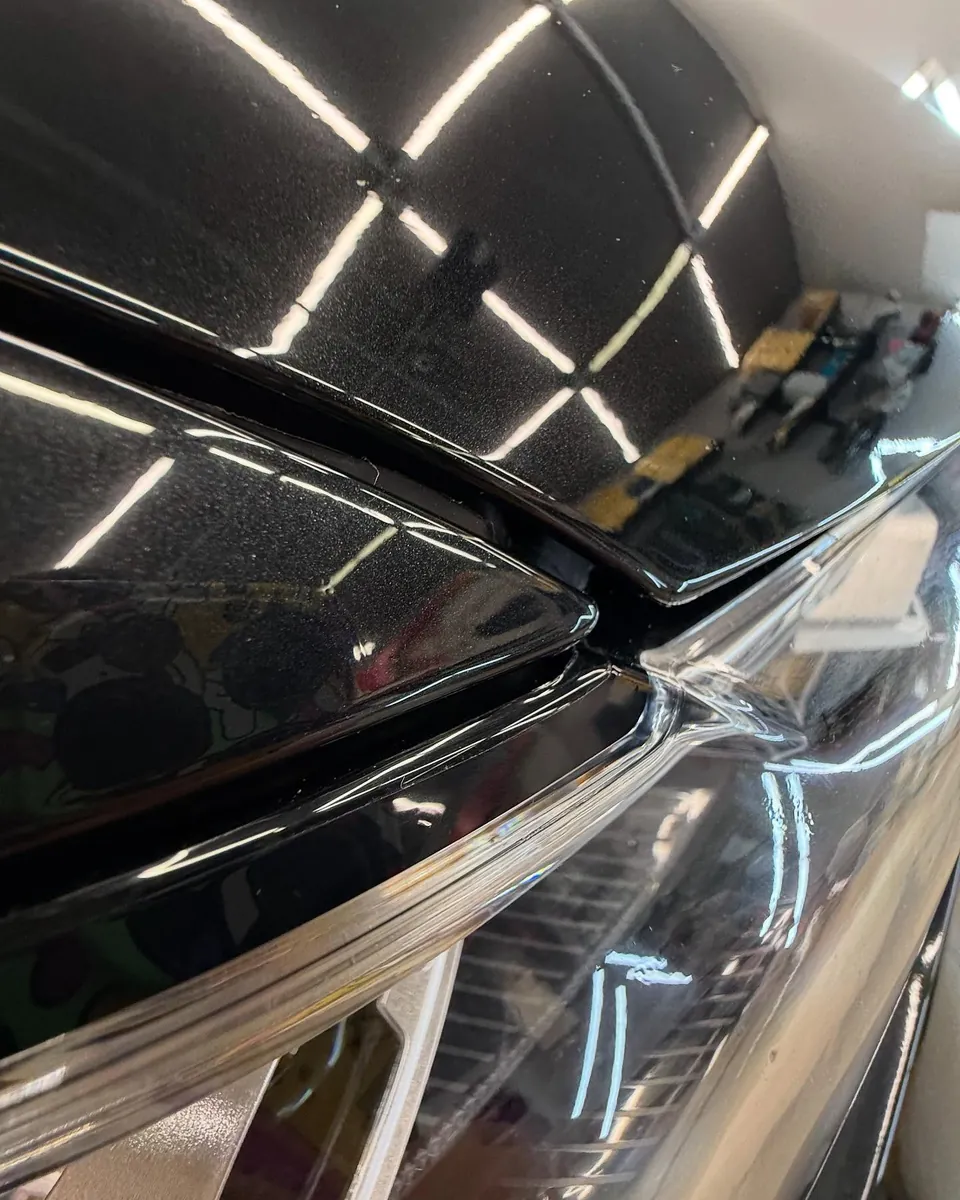 Фара и капот чёрного BMW X7 после полной оклейки плёнкой