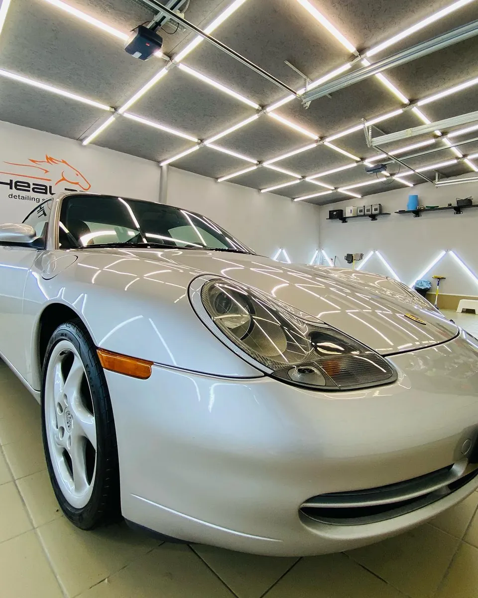 Серебристый Porsche 911 (996) в боксе после работы с фарами